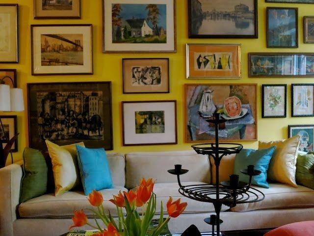 Eclectic salon wall of framed artwork above a colorful sofa