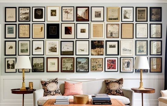 Salon wall with evenly arranged framed artwork above a sofa